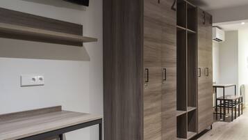 Una habitación moderna con un armario de madera, un televisor de pantalla plana en la pared y una pequeña mesa con dos taburetes.