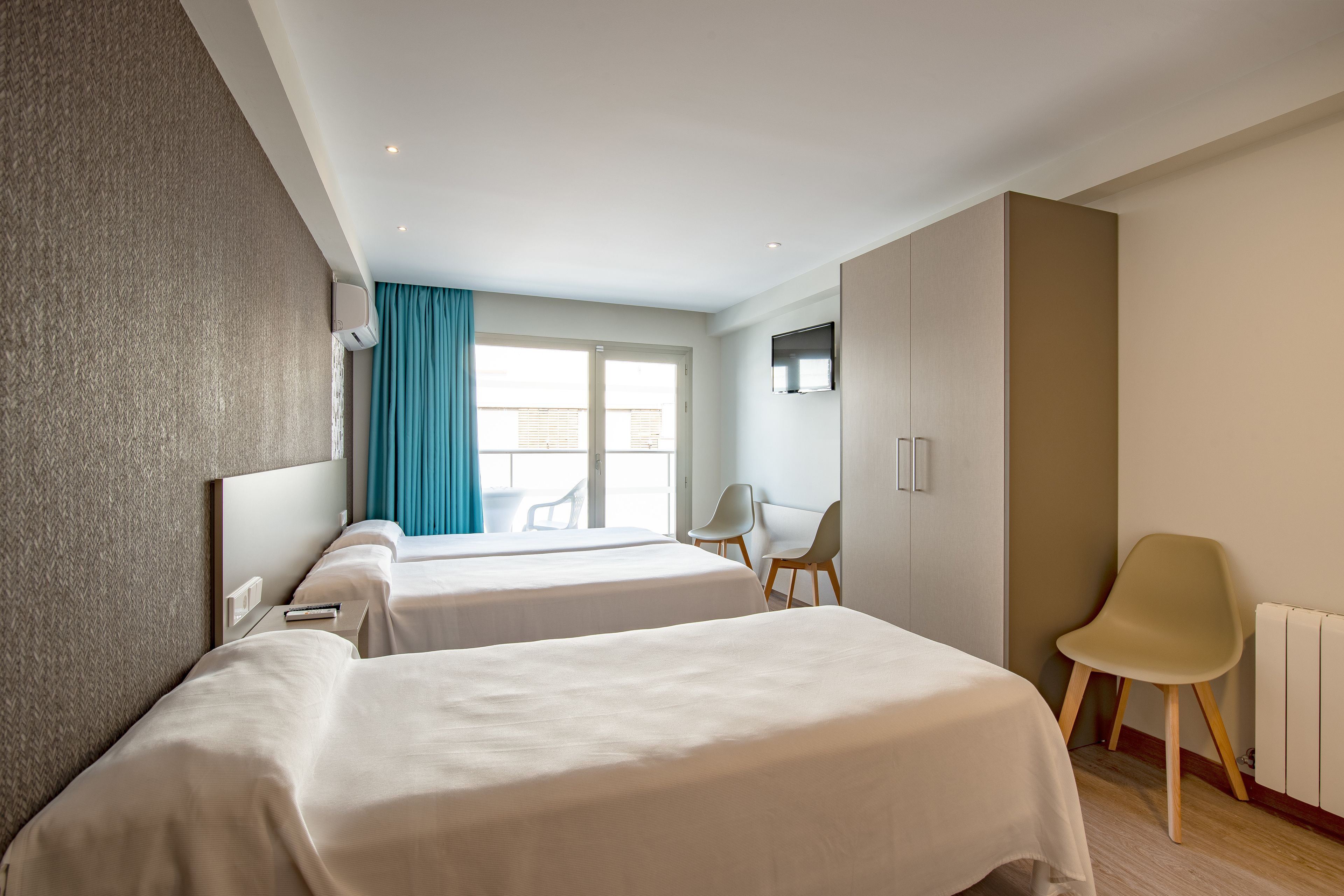 Een hotelkamer met twee bedden, een televisie, een raam met gordijnen en een stoel.
