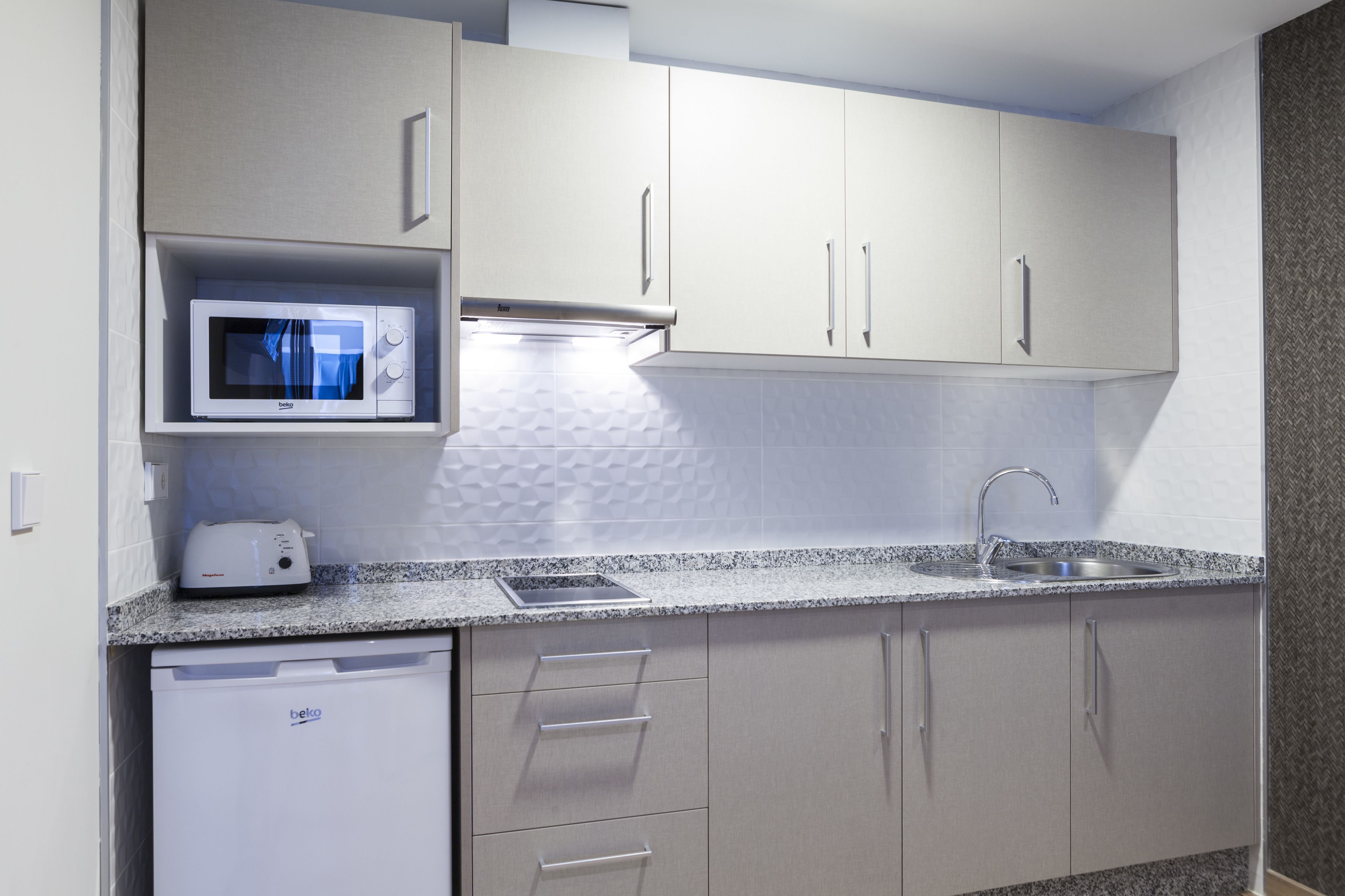 A modern kitchen with a built-in microwave, toaster, and dishwasher.