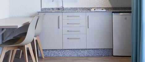 A compact kitchen with a dining area, featuring a microwave, sink, and cabinets.