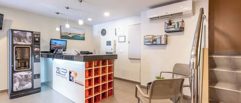 A reception area with a counter, a coffee machine, a television, and a seating area with chairs.