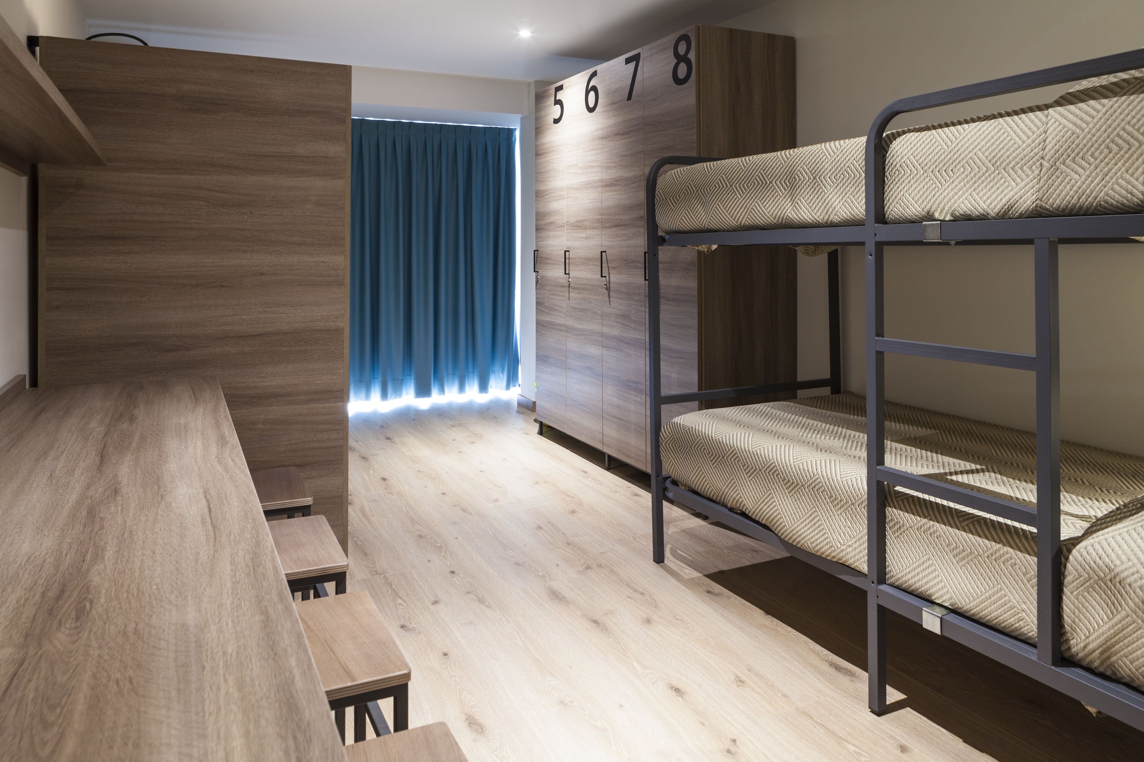 A bunk room with a bunk bed, a desk, and a wardrobe.