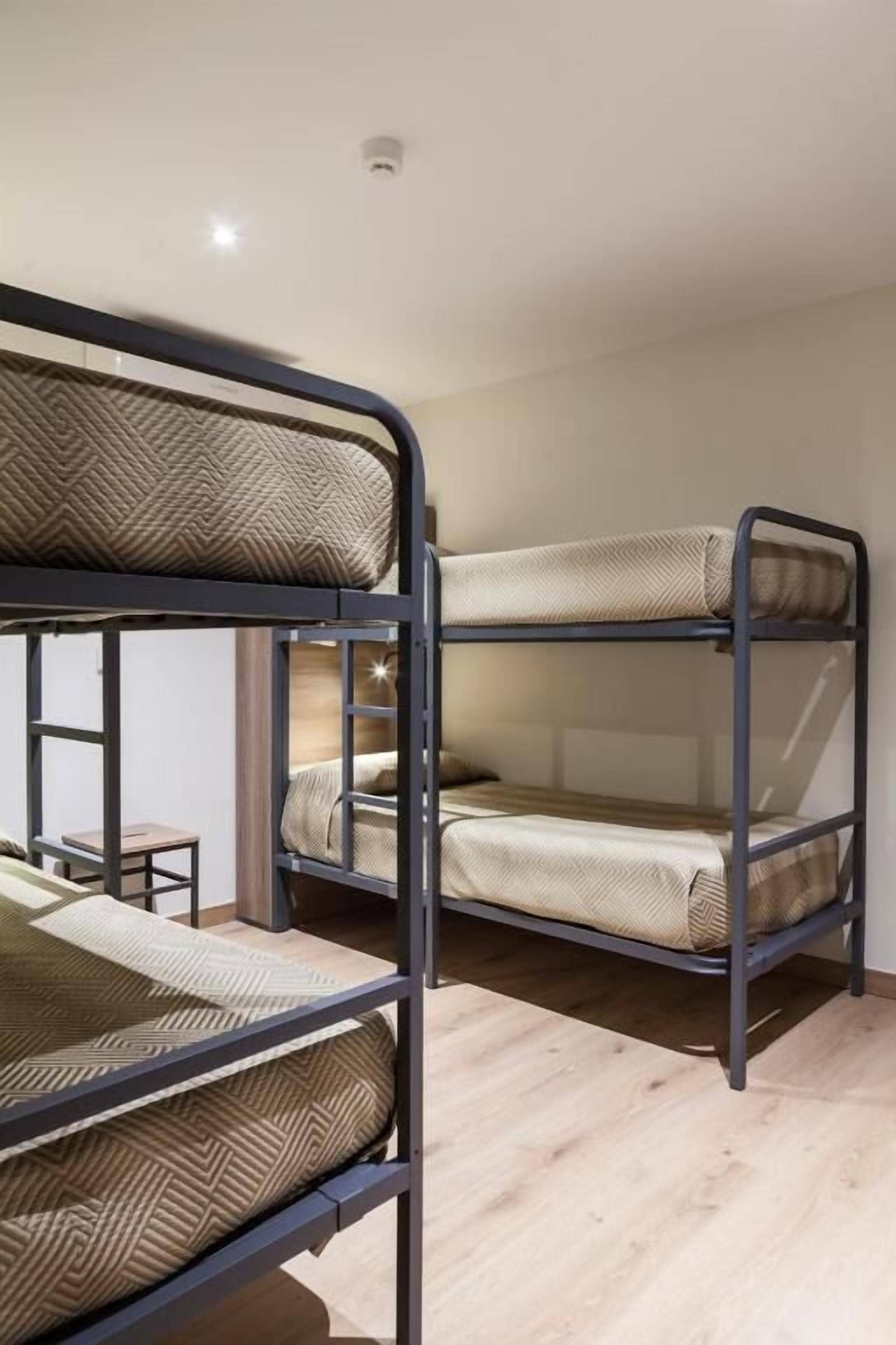 Habitación con literas, una mesita pequeña y una silla.