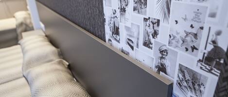 A wall with a collage of black and white photos, a patterned rug, and a bed with pillows.