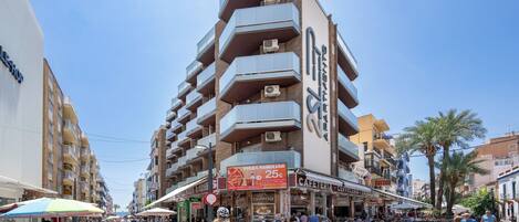 A multi-story building with balconies, outdoor seating, and various shops.