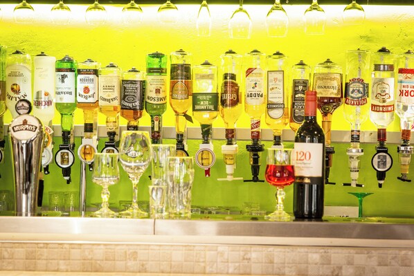 Un bar con varias botellas de licor y vasos a la vista.