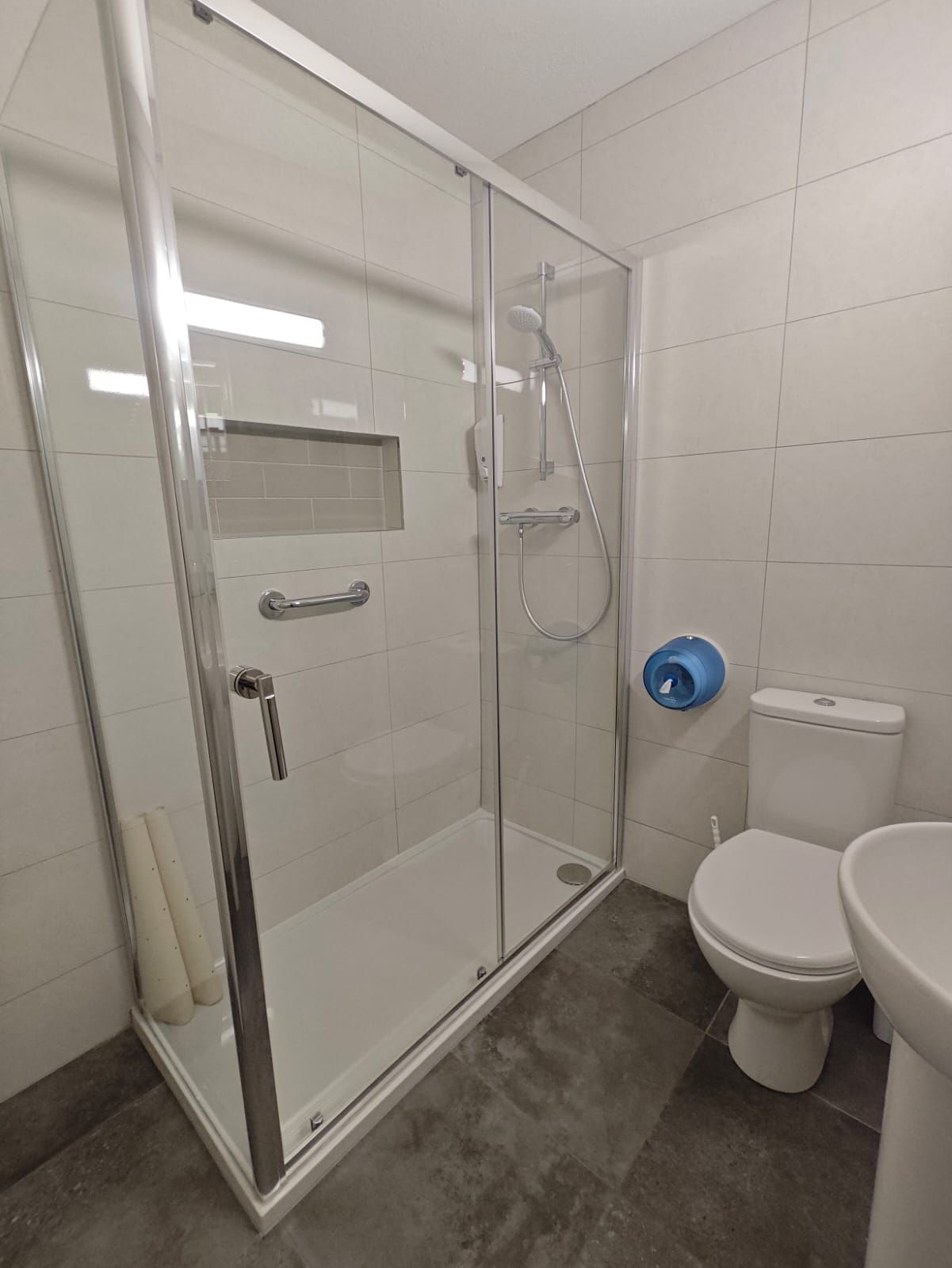 A modern bathroom with a glass-enclosed shower, a toilet, and a sink.