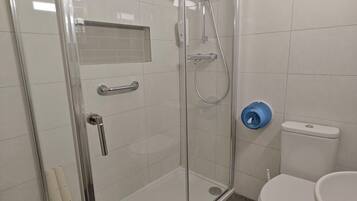 A modern bathroom with a glass-enclosed shower, a toilet, and a sink.