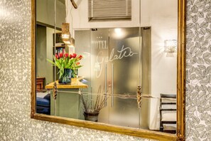 A hotel room with a large mirror reflecting a vase of red tulips, a potted plant, and a bed. - Boutique Hotel Galatea (Rome)