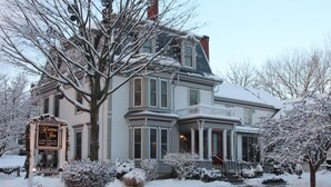 A Victorian-style hotel with a snow-covered exterior, a prominent front porch, and a sign indicating it is a lodging and fine dining establishment. - Hartstone Inn (Camden)