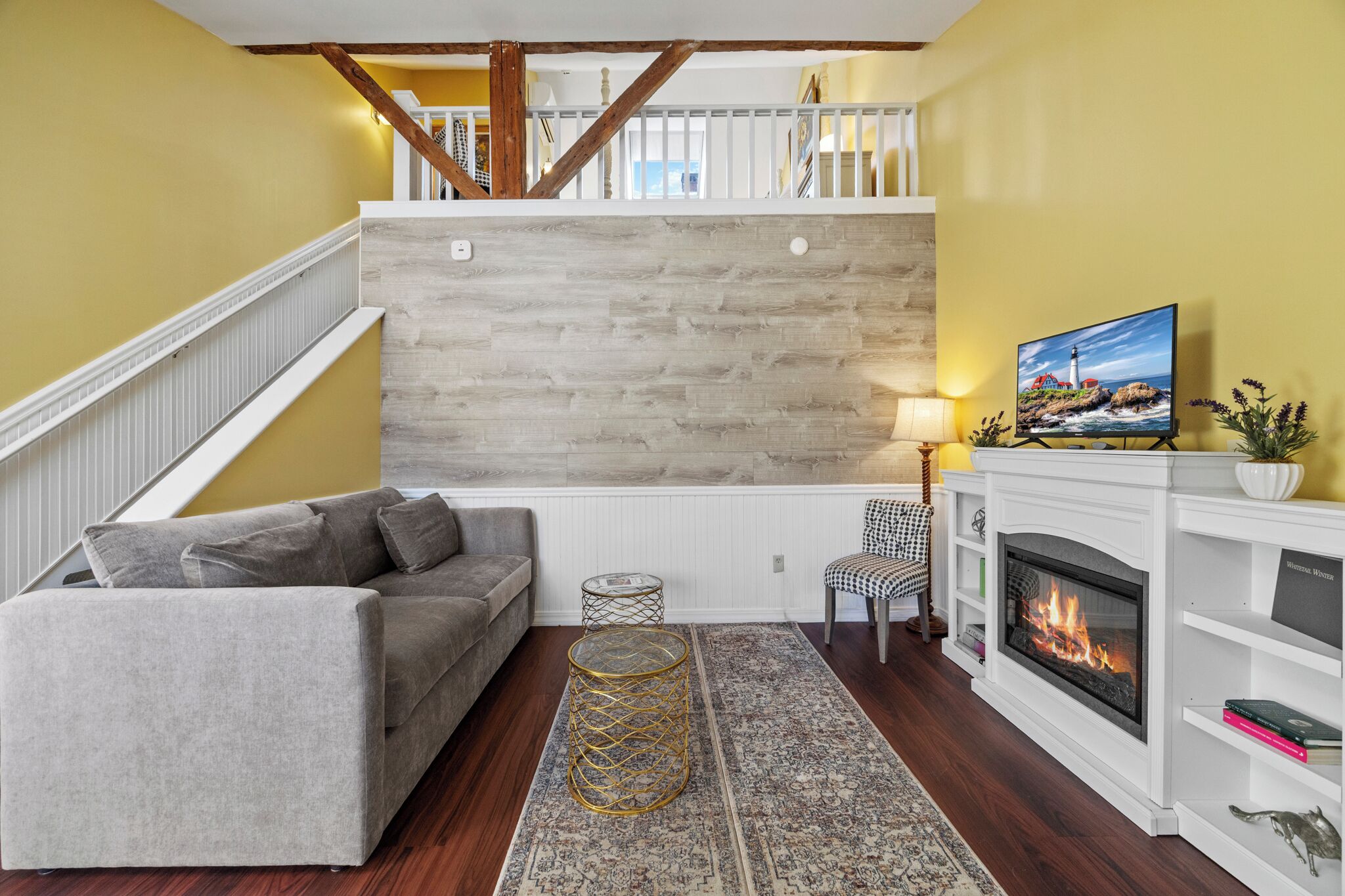 Una sala de estar con chimenea, sofá, alfombra estampada y televisor.