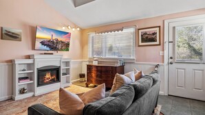 A living room with a fireplace, a sofa, a television, and a door with a view. - Hartstone Inn (Camden)