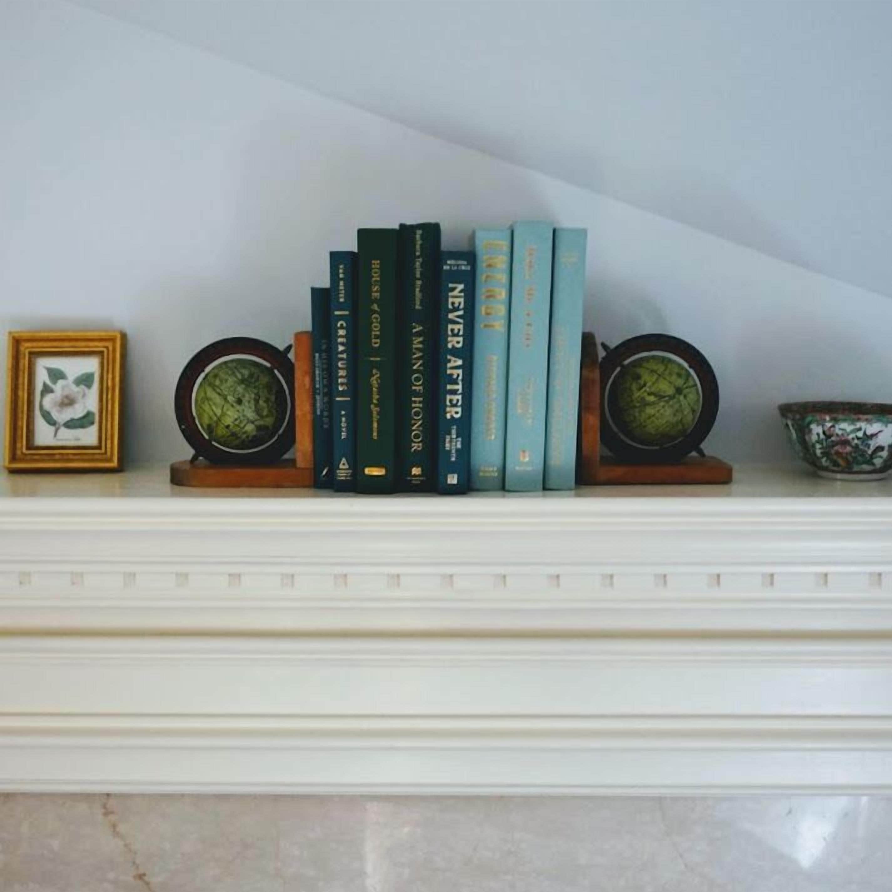 A bookshelf with books and decorative items on a mantelpiece.