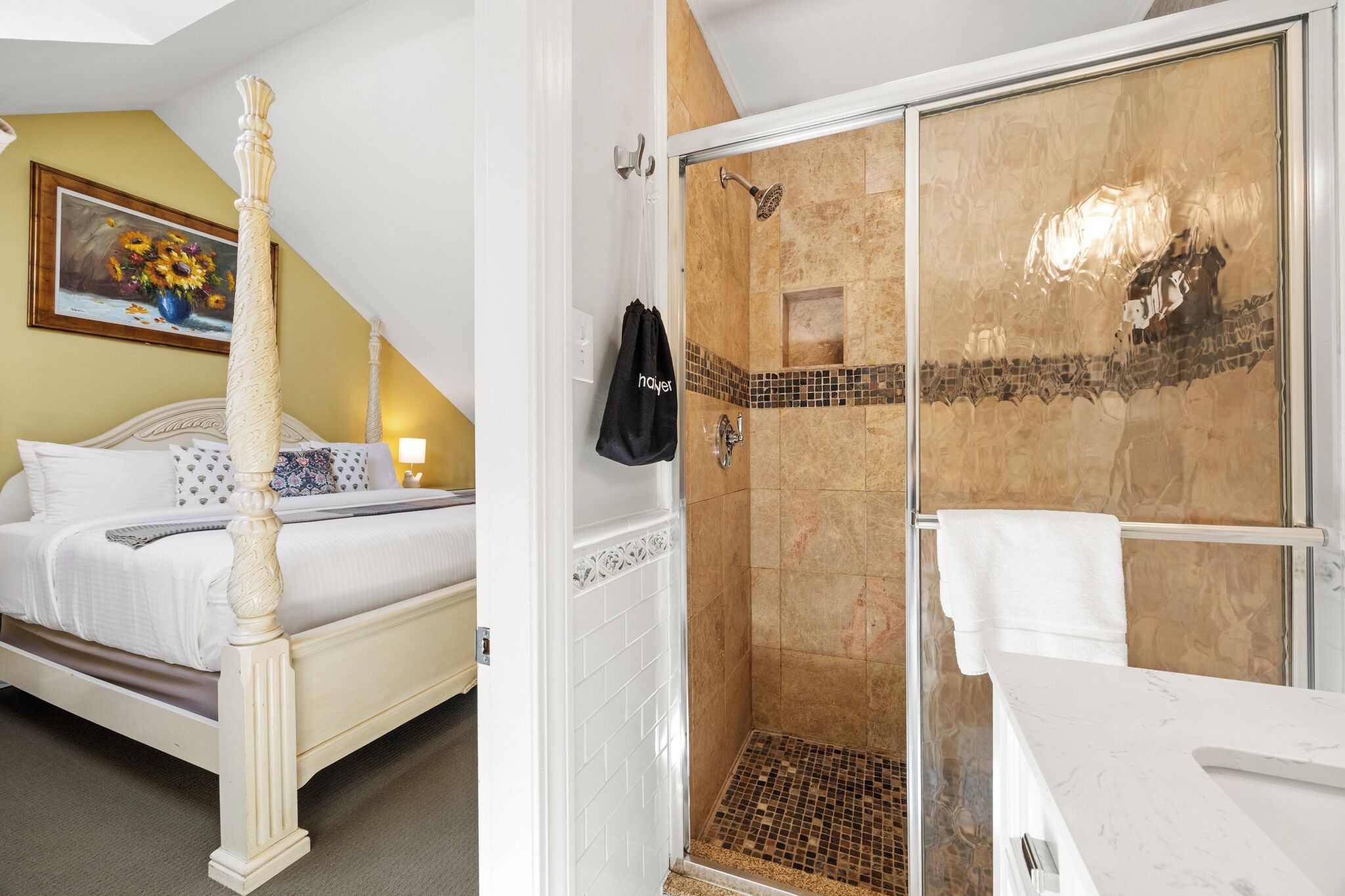 A bedroom with a four-poster bed and a shower area with a glass door.