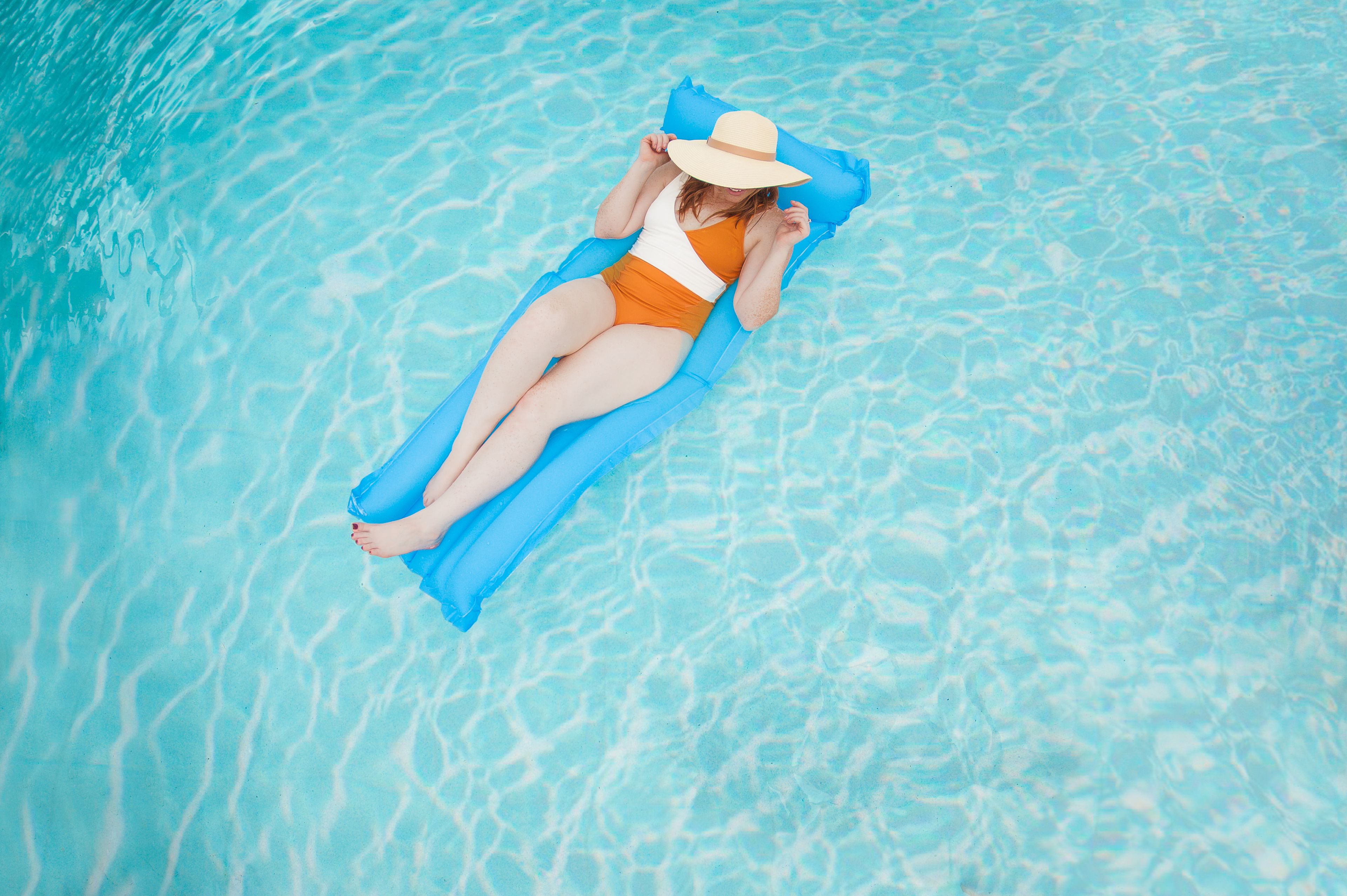 Uma pessoa deitada em um flutuador azul numa piscina.