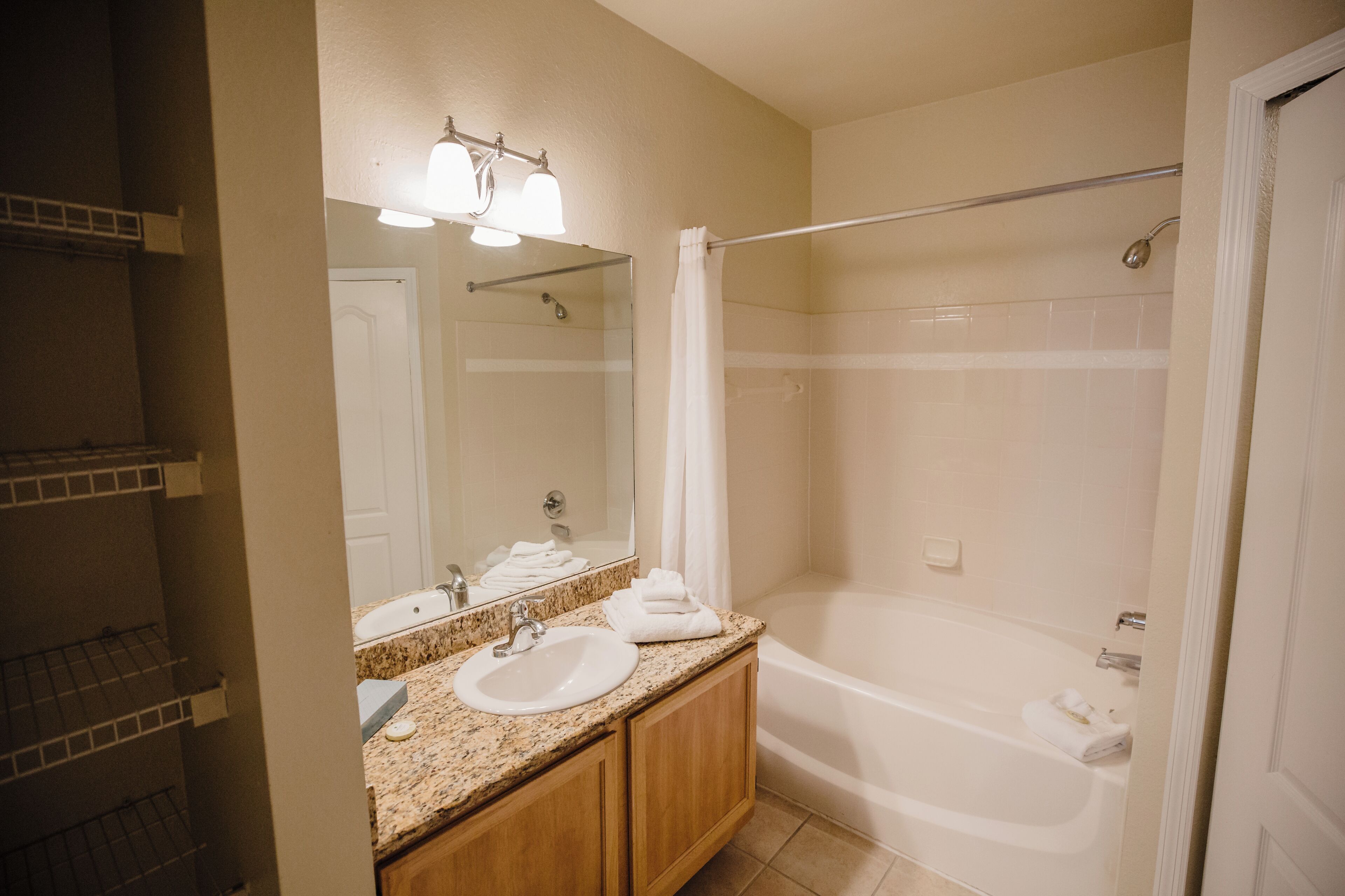 A bathroom with a sink, mirror, and shower.