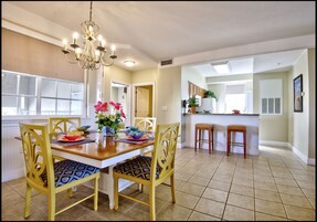 Uma sala de jantar com uma mesa de madeira, cadeiras amarelas e um candelabro.