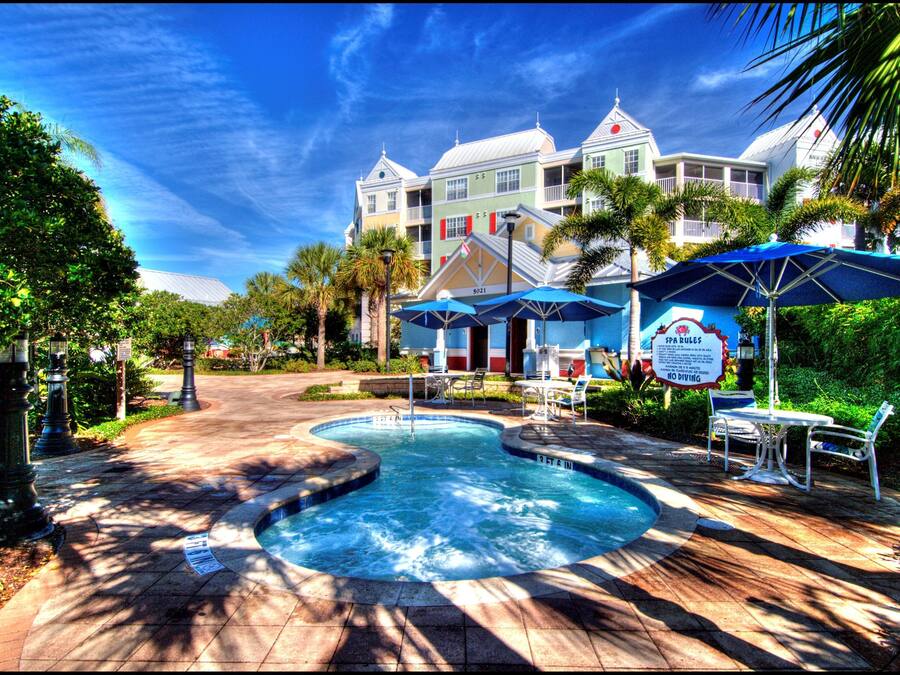 A hotel with a swimming pool, outdoor seating, and a large building in the background.