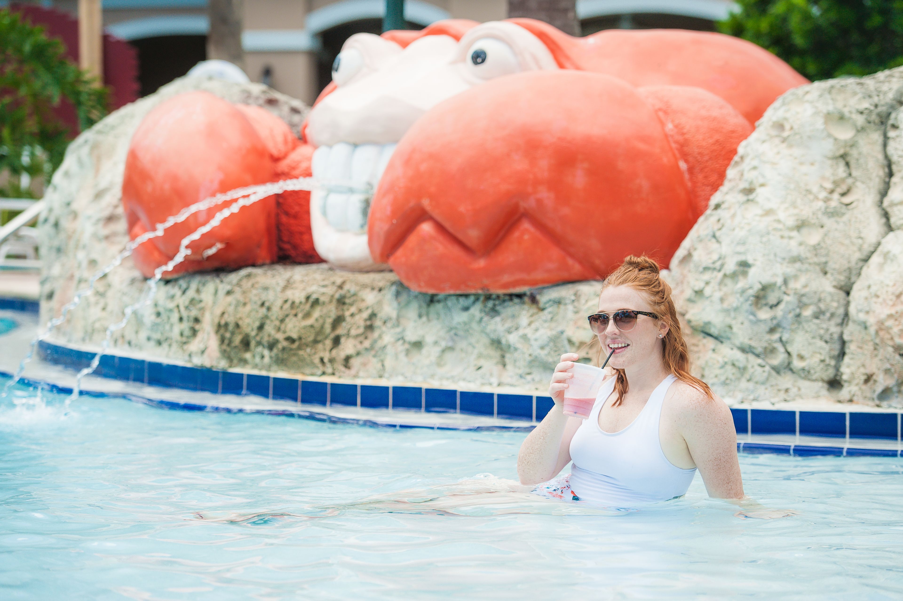 A person in a swimming pool with a large plush toy in the background.