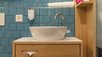 A bathroom with a white sink, wooden vanity, and blue tiled walls.