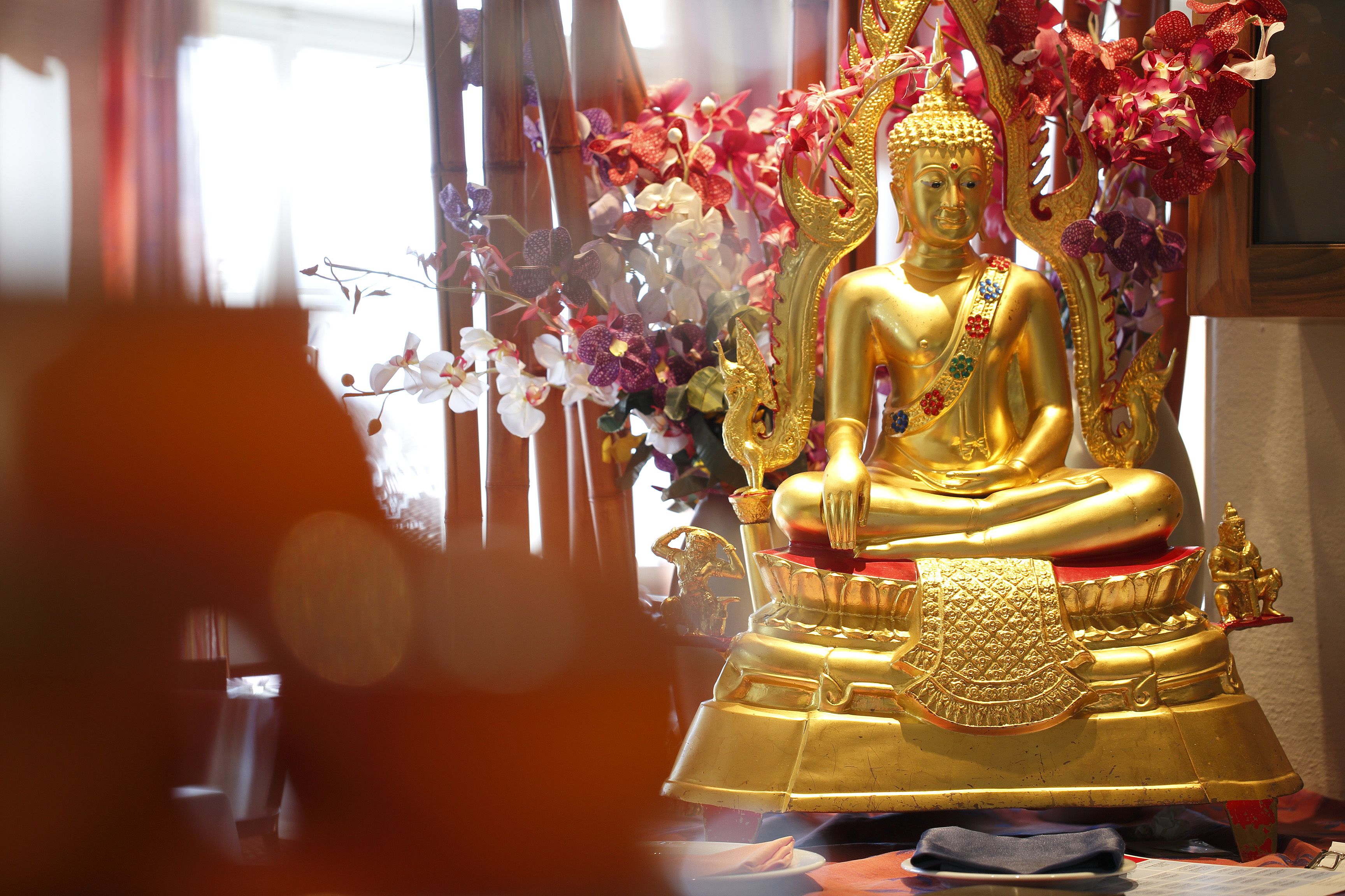 Una estatua dorada de Buda con detalles intrincados y un paño rojo y dorado.