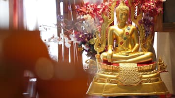 Una estatua dorada de Buda con detalles intrincados y un paño rojo y dorado.