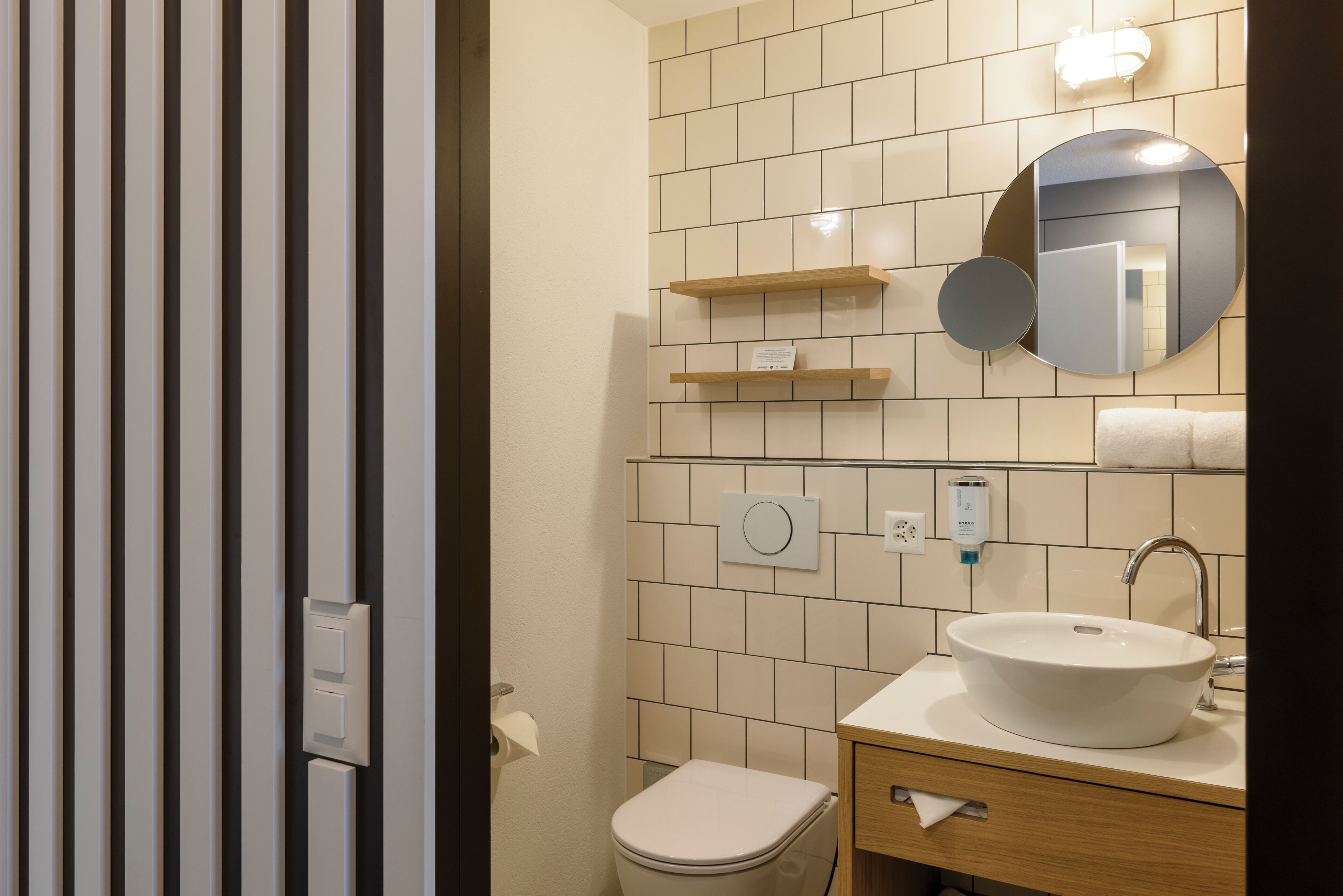 A bathroom with a toilet, sink, mirror, and towel rack.