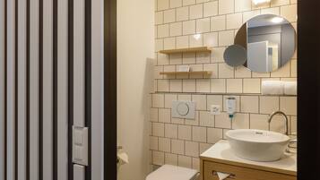 A bathroom with a toilet, sink, mirror, and towel rack.