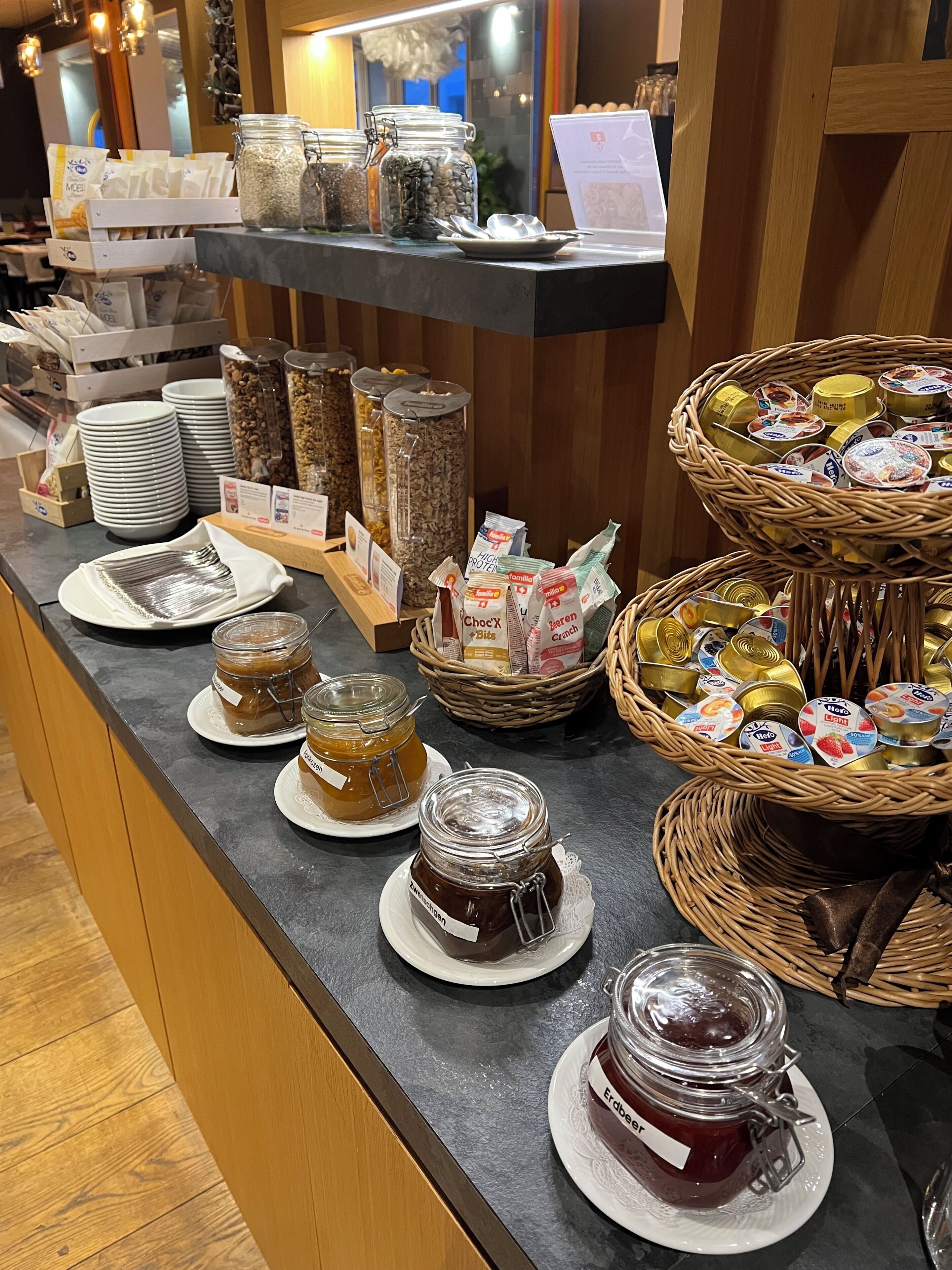 A buffet counter with various food items, including jars of preserves and packaged snacks.