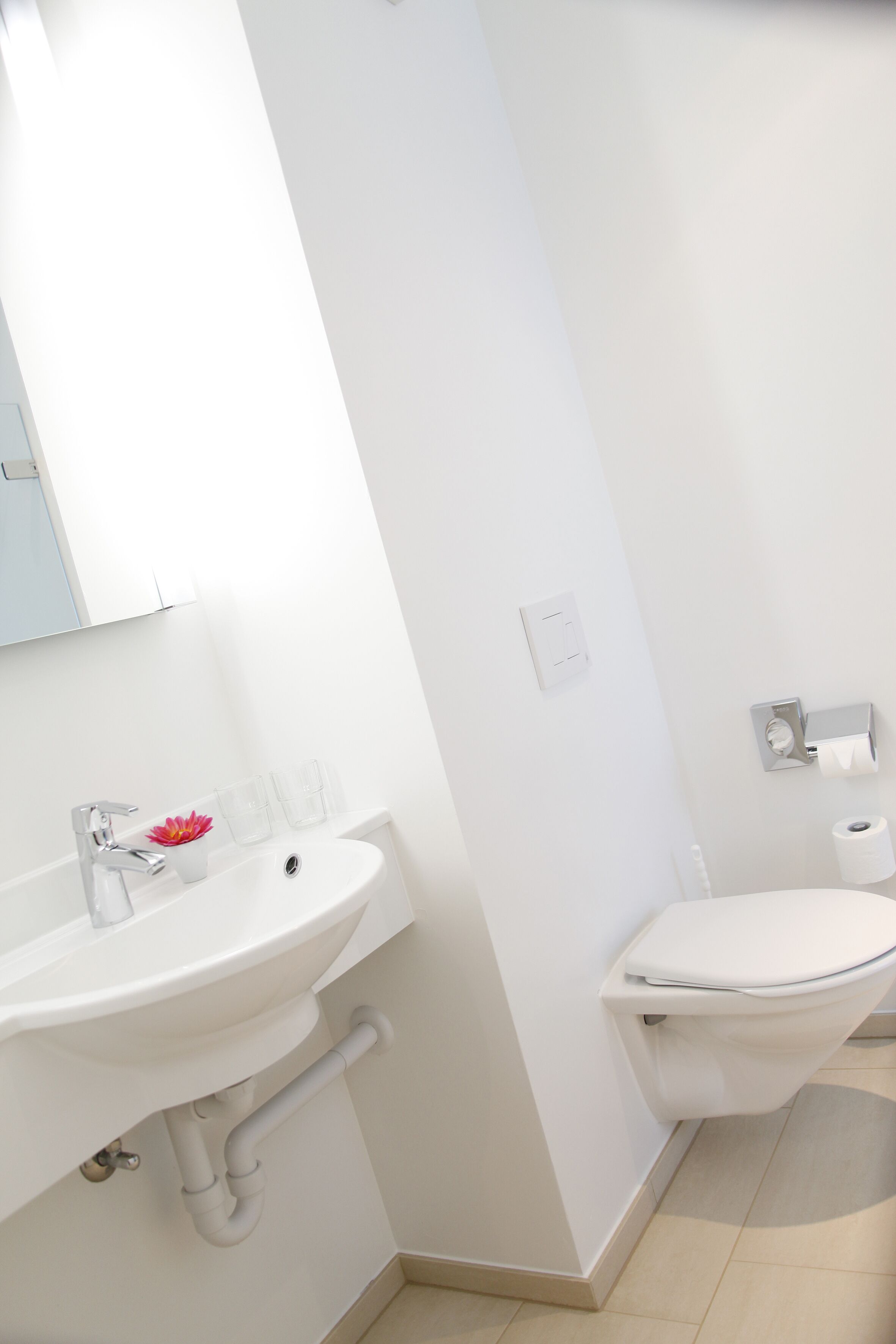 A bathroom with a white sink, mirror, and toilet.