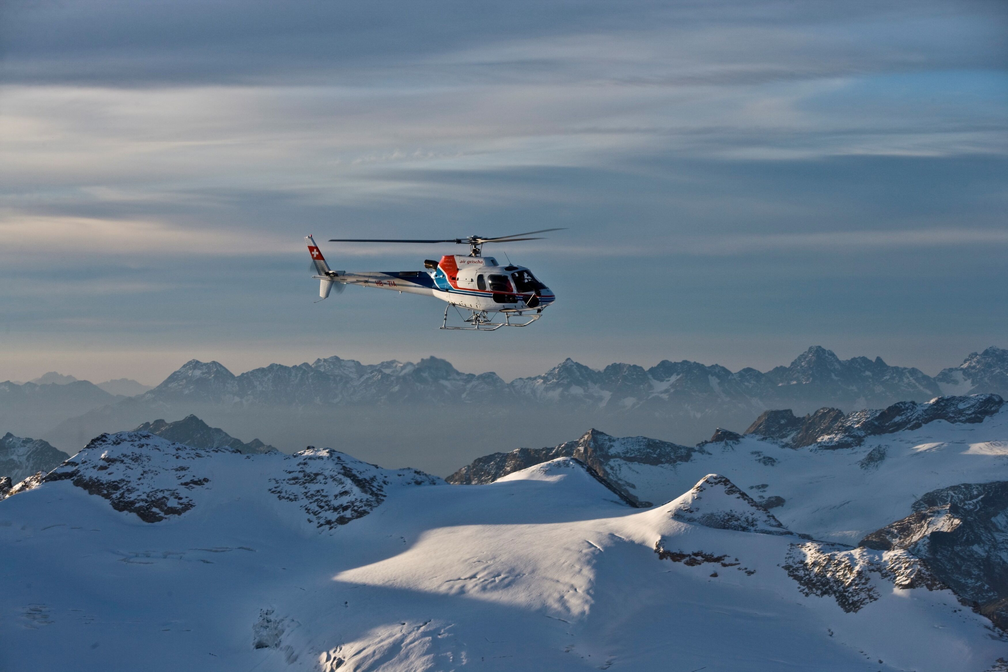 Un helicóptero volando sobre una cordillera nevada.