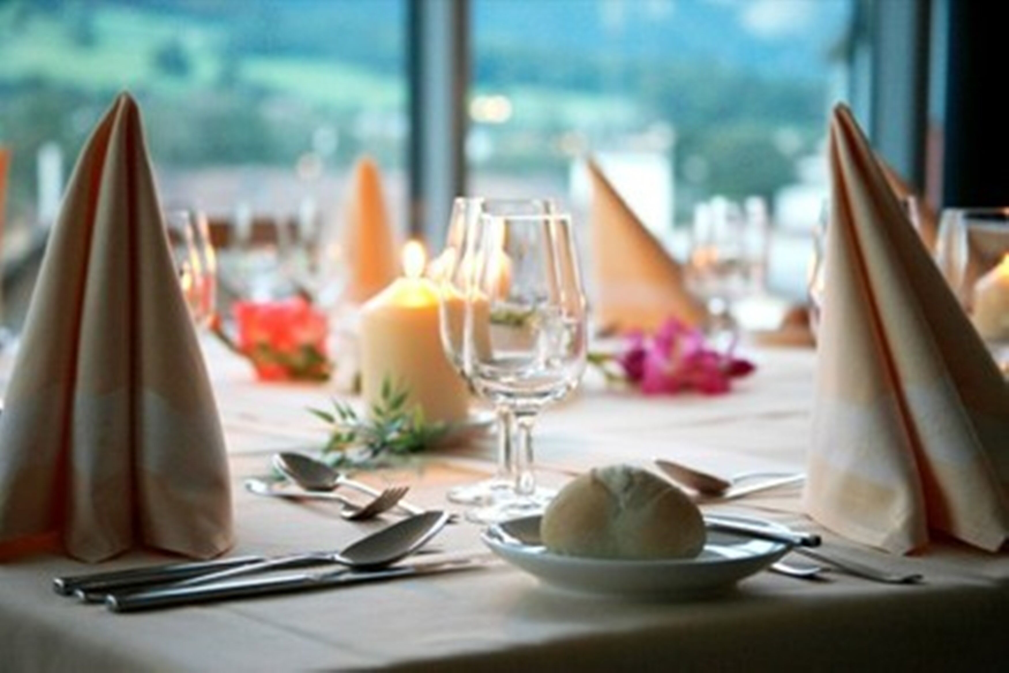 A table set for dining with a candle, wine glass, and a plate of food.