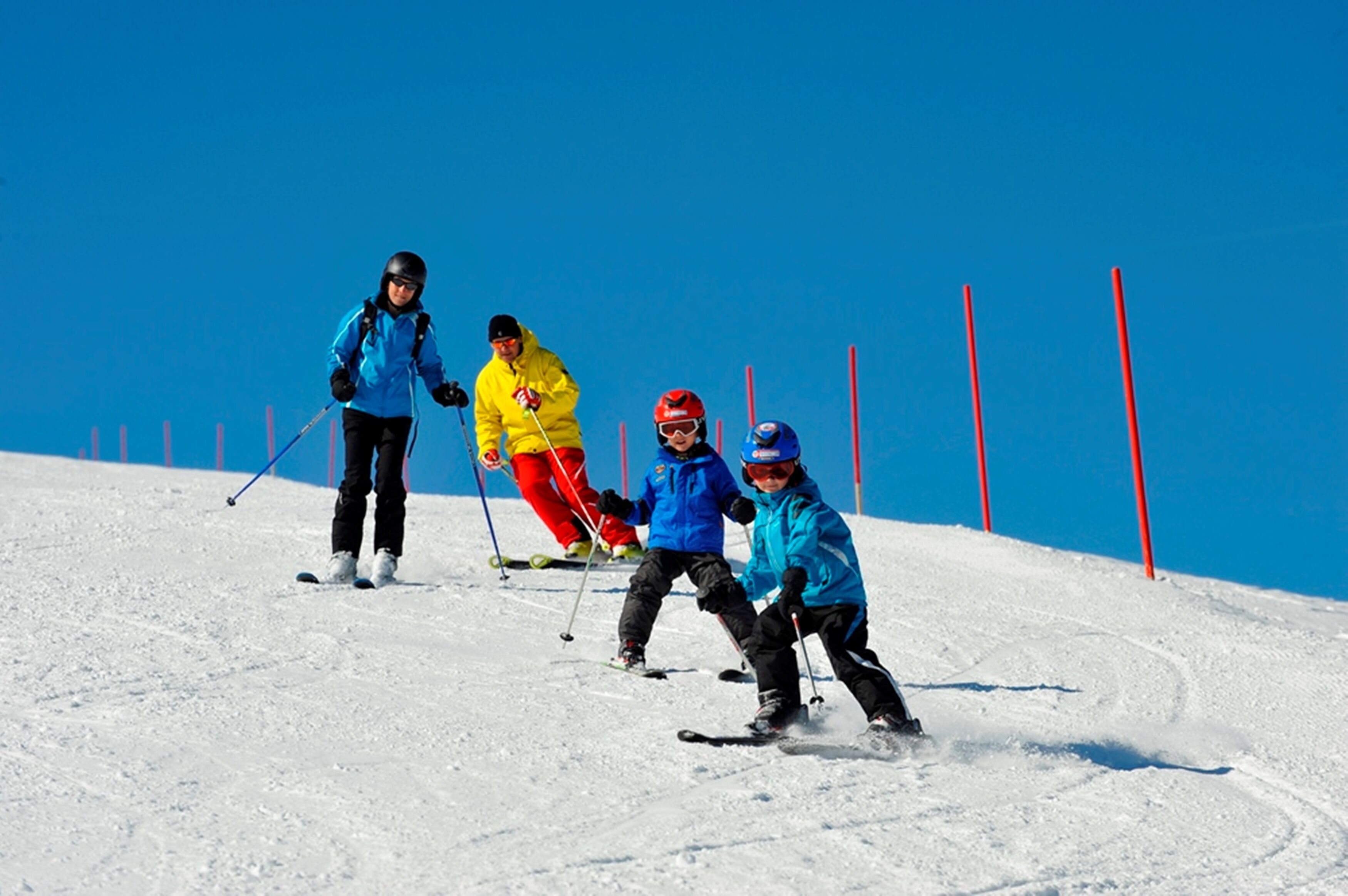 A group of skiers on a snowy slope with a clear blue sky.