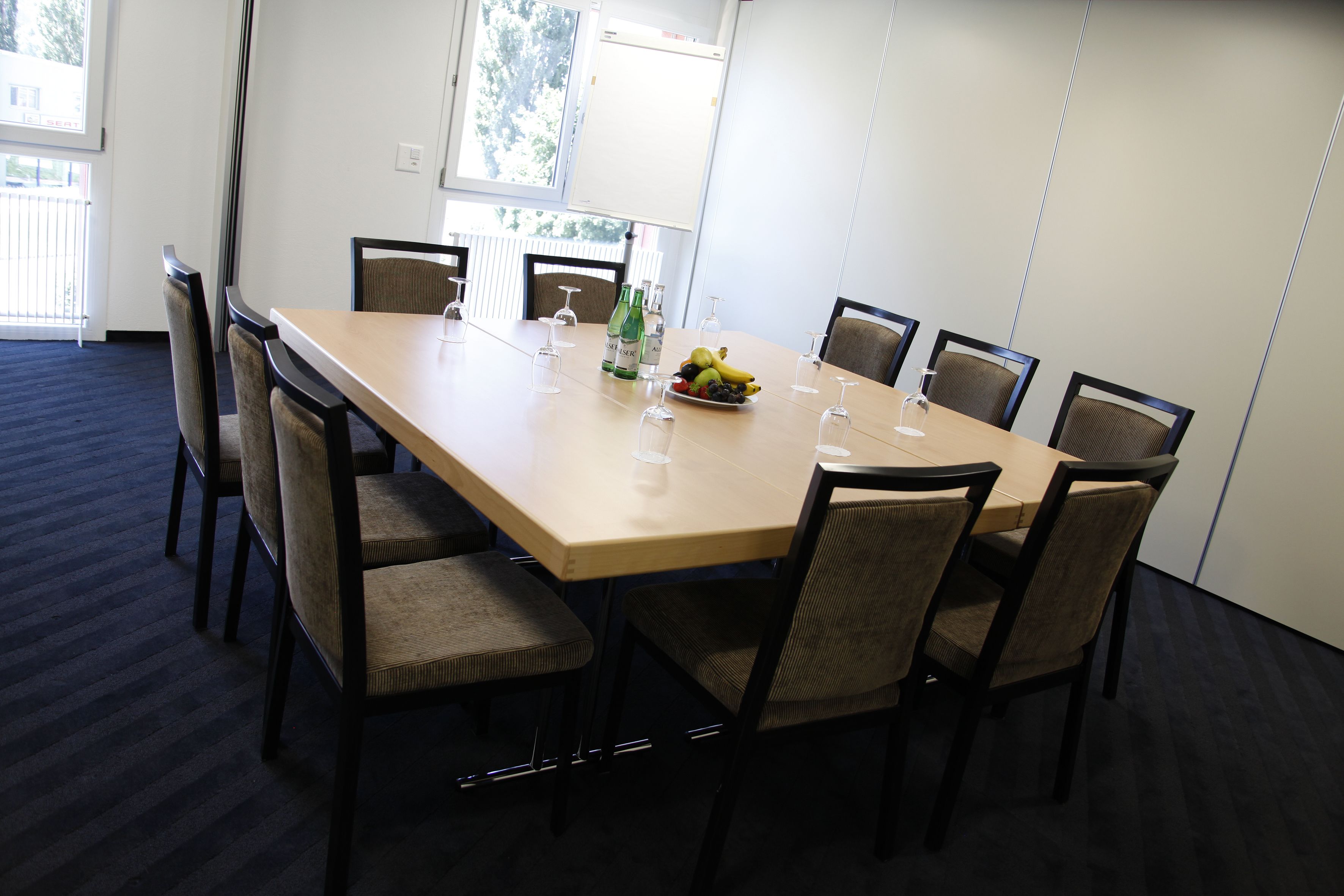 A conference room with a long table, chairs, and a fruit bowl.