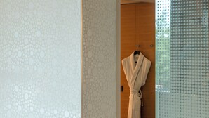 A bathroom with a patterned wall, a wooden door, and a white robe hanging on a hook. - Sofitel Luxembourg Le Grand Ducal (Luxembourg City)