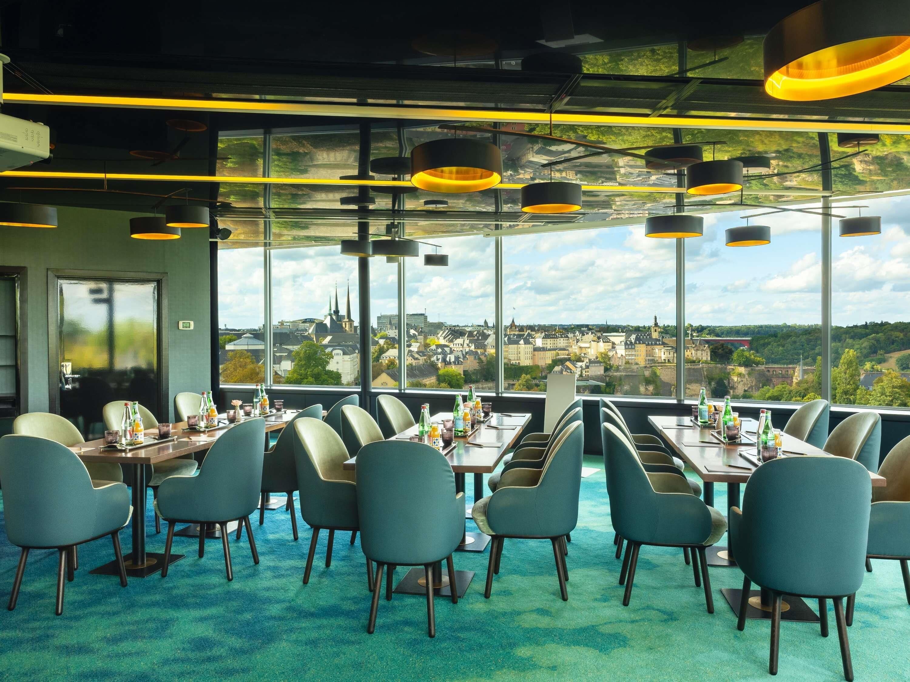 Restaurante con vistas a un paisaje urbano, con mesas y sillas dispuestas para comer.