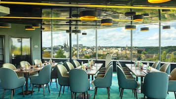 Restaurante con vistas a un paisaje urbano, con mesas y sillas dispuestas para comer.