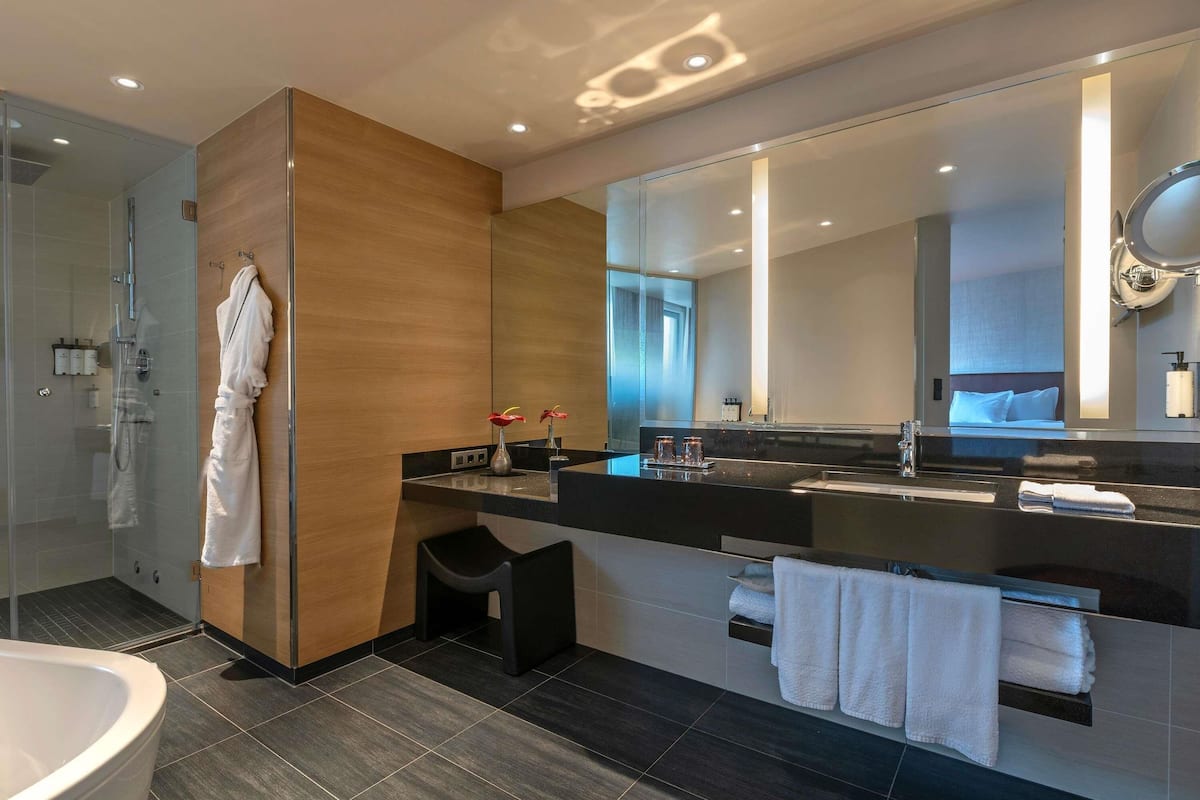 Ein modernes Badezimmer mit Duschkabine aus Glas, großem Spiegel, Badewanne und Waschtisch mit Handtuchhalter.