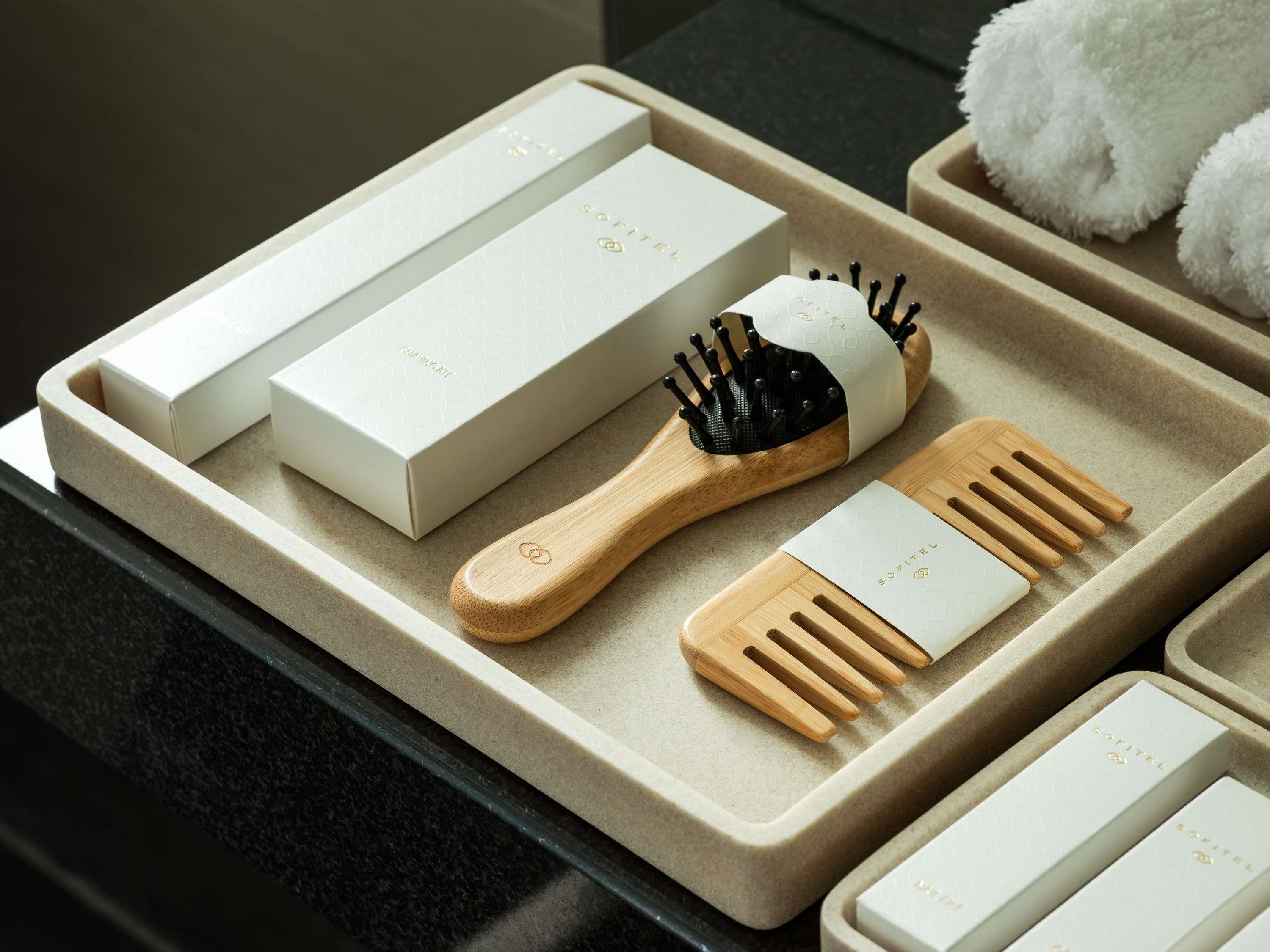 Bandeja con un cepillo de madera, un peine y cajas blancas con un logotipo.