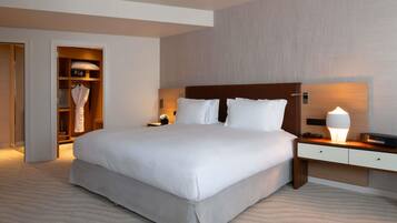 A hotel room with a large bed, bedside tables, a nightstand, a lamp, a wardrobe, and a mirror.