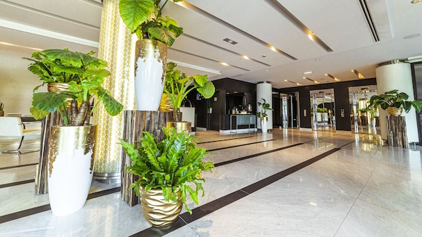 A spacious lobby with large potted plants, a reception desk, and a modern interior design. - Sofitel Luxembourg Le Grand Ducal (Luxembourg City)