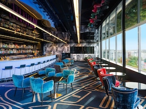 A modern bar area with a long counter, bar stools, and a seating area with chairs and tables. - Sofitel Luxembourg Le Grand Ducal (Luxembourg City)