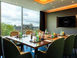 A meeting room with a large table, chairs, and a city view.