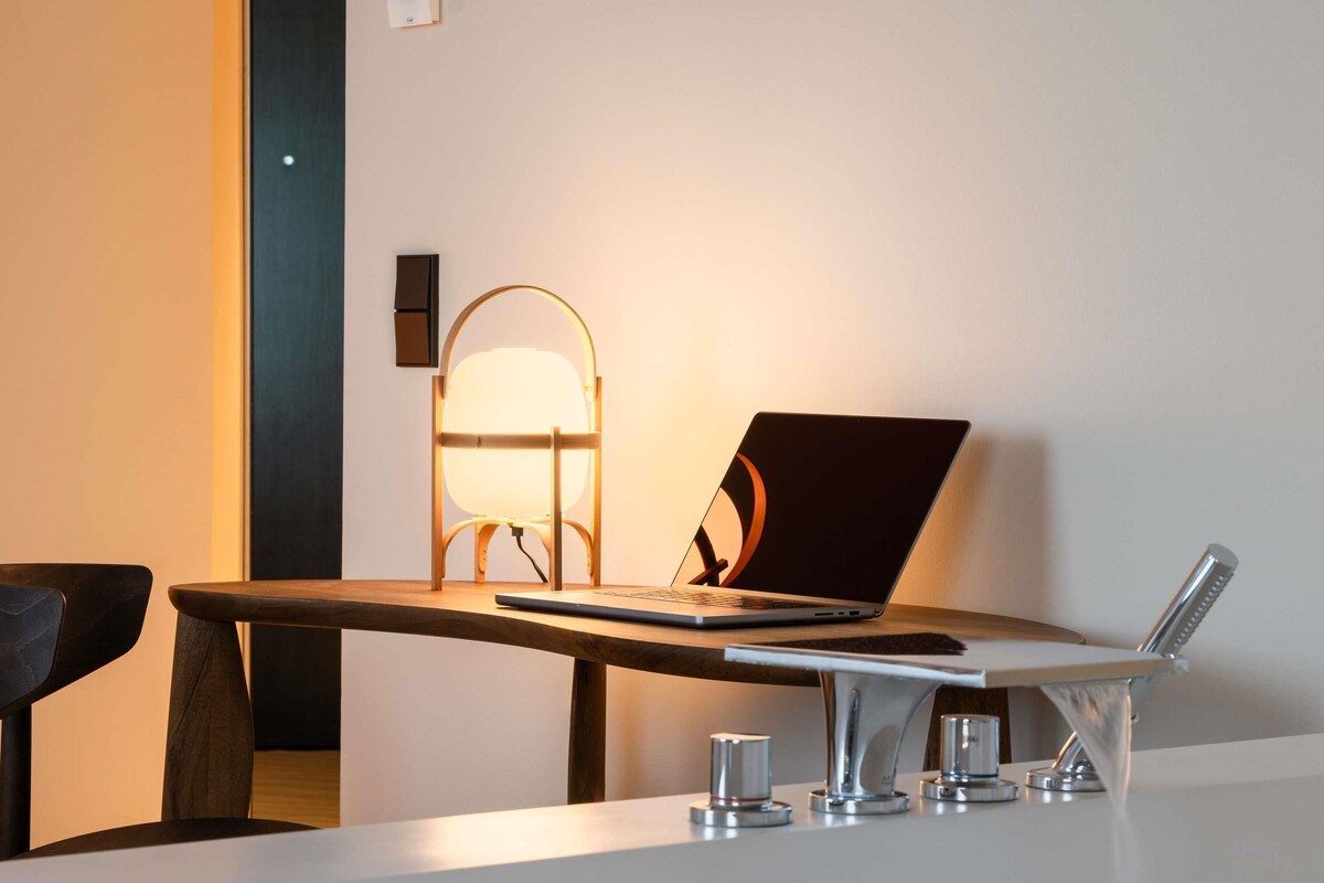 A modern office desk with a laptop, a lamp, and a glass of water.