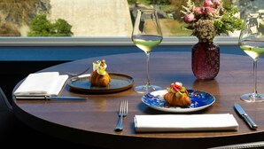 A table with a croissant, a glass of white wine, and a vase with flowers. - Sofitel Luxembourg Le Grand Ducal (Luxembourg City)