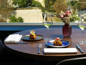 A table with a croissant, a glass of white wine, and a vase with flowers. - Sofitel Luxembourg Le Grand Ducal (Luxembourg City)