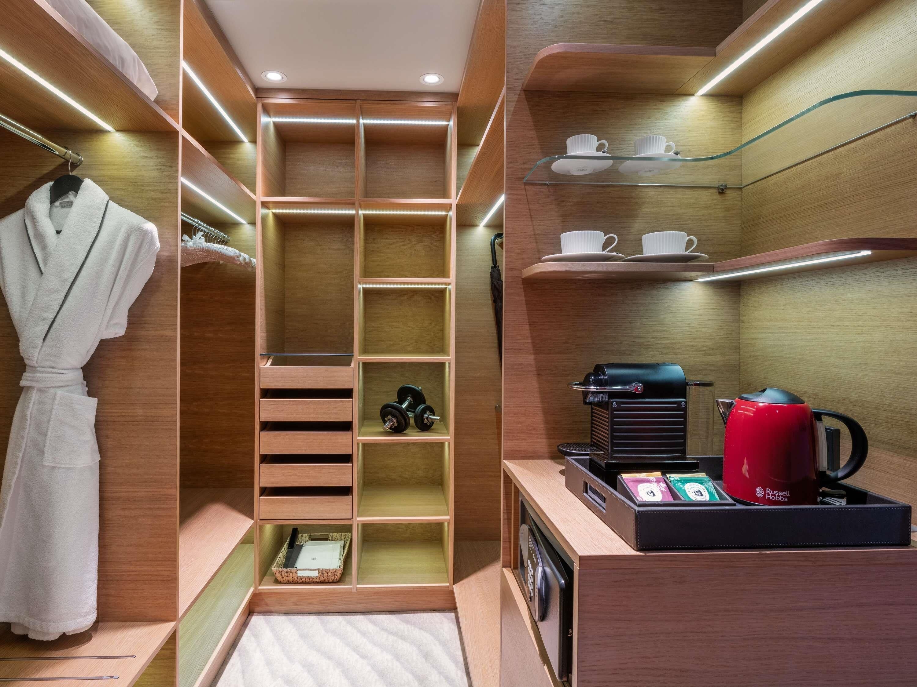 Un baño moderno con cabina de ducha, una bata colgada, una cafetera y un hervidor de agua.