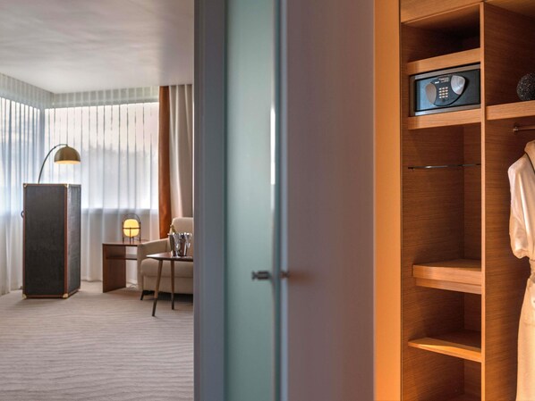 Una habitación de hotel con un armario de madera, un escritorio con lámpara, una silla y una cama.
