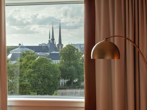 A window with a view of a church with two spires, a lamp, and curtains. - Sofitel Luxembourg Le Grand Ducal (Luxembourg City)