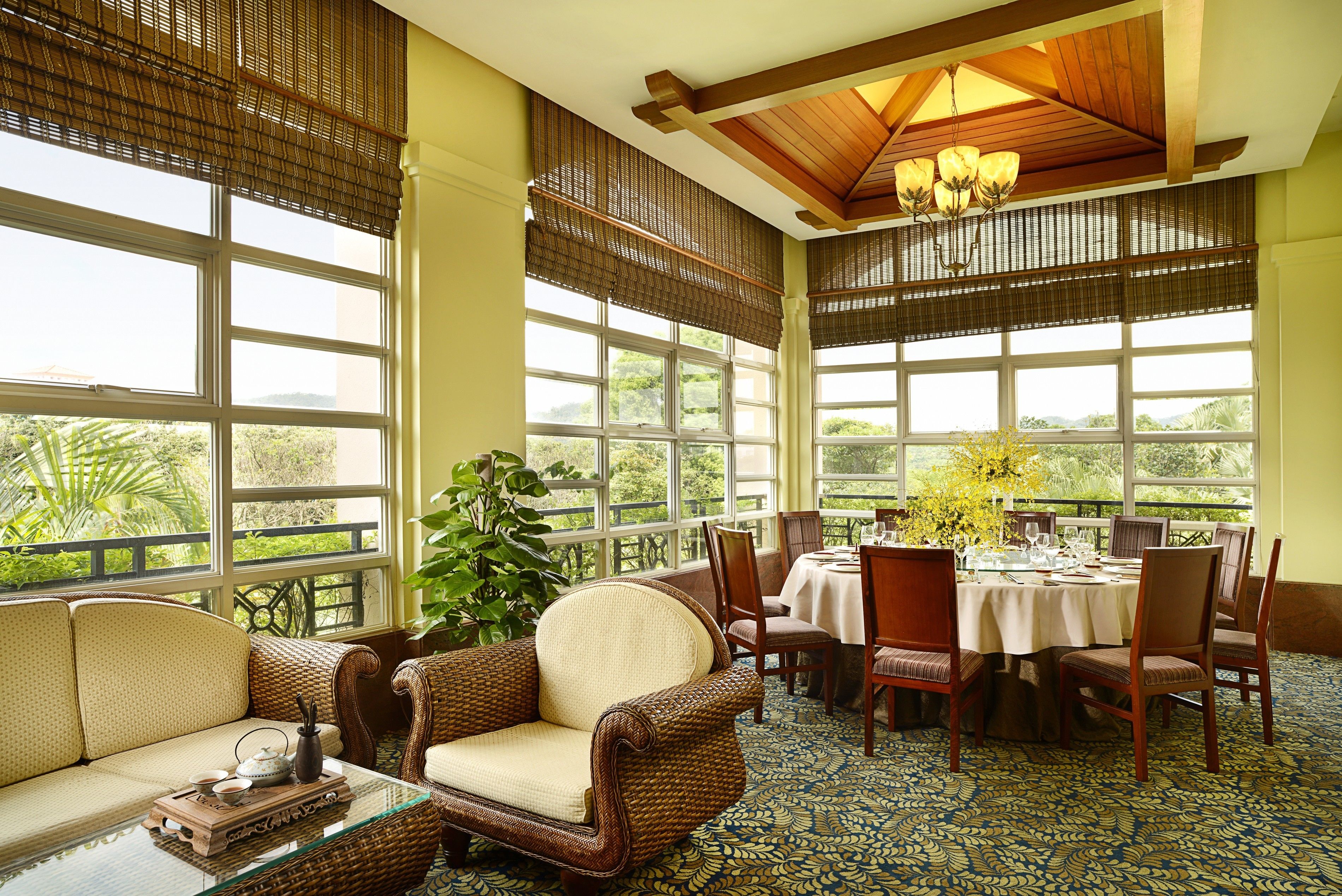 A spacious room with large windows, a dining area, and a seating area with a sofa and chairs.